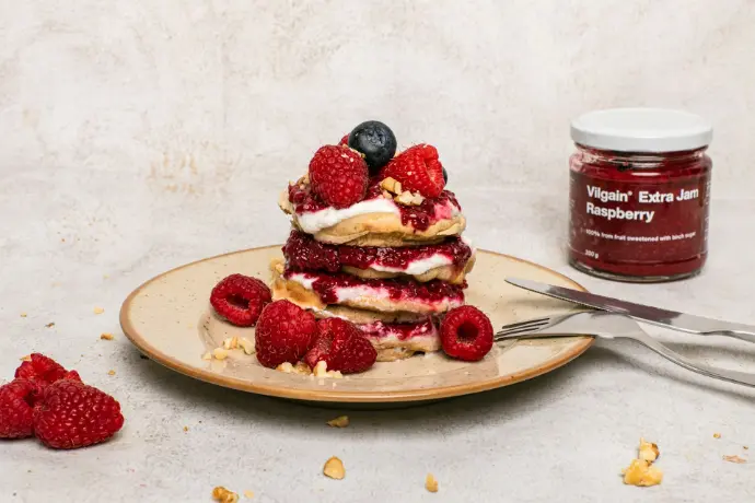 a stack of pancakes topped with berries and whipped cream