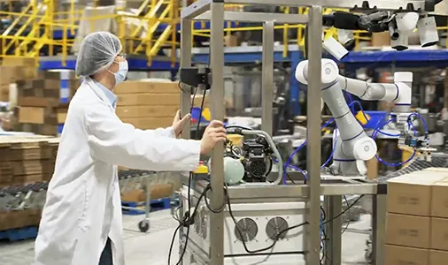Τεχνικός δίπλα στο cobot σε γραμμή τροφίμων